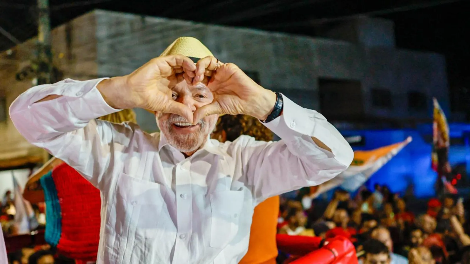 Lula faz um coração com as mãos para o público em um comício
